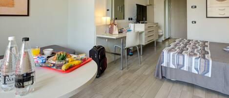 A hotel room with a desk, a bed, a mirror, a wardrobe, and a bathroom visible through an open door.