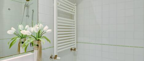 Un baño con una bañera blanca, un toallero blanco y un espejo que refleja la zona de la ducha.