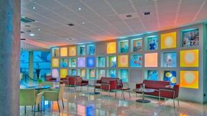 A modern lobby with a tiled floor, red seating, and colorful artwork on the walls. - Parc Hotel (Castelnuovo del Garda)