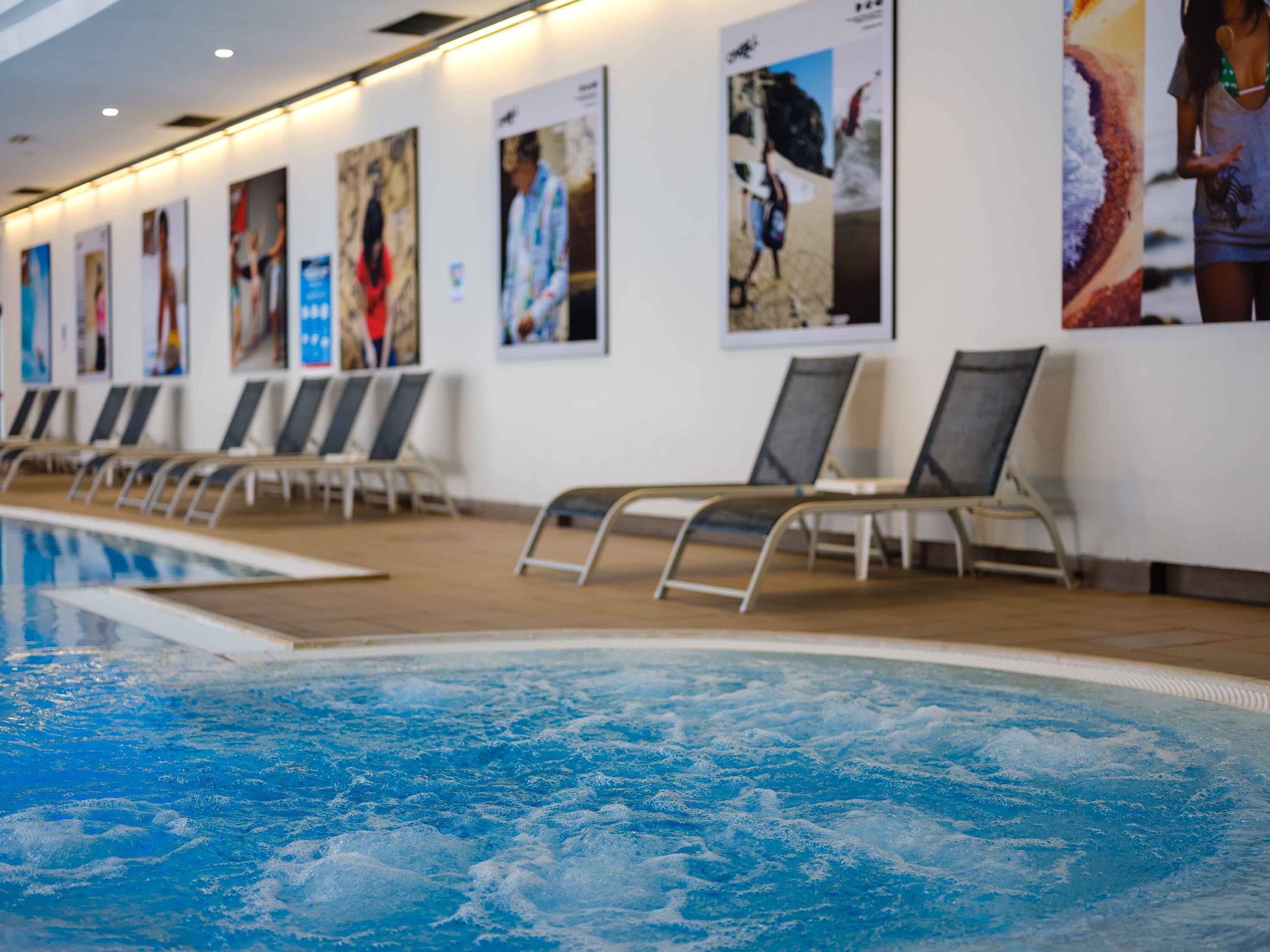 A swimming pool with lounge chairs and posters on the wall.