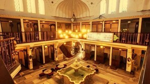 Un atrium espaiós de diversos nivells, amb una font central, baranes ornamentals i una gran pèndol.