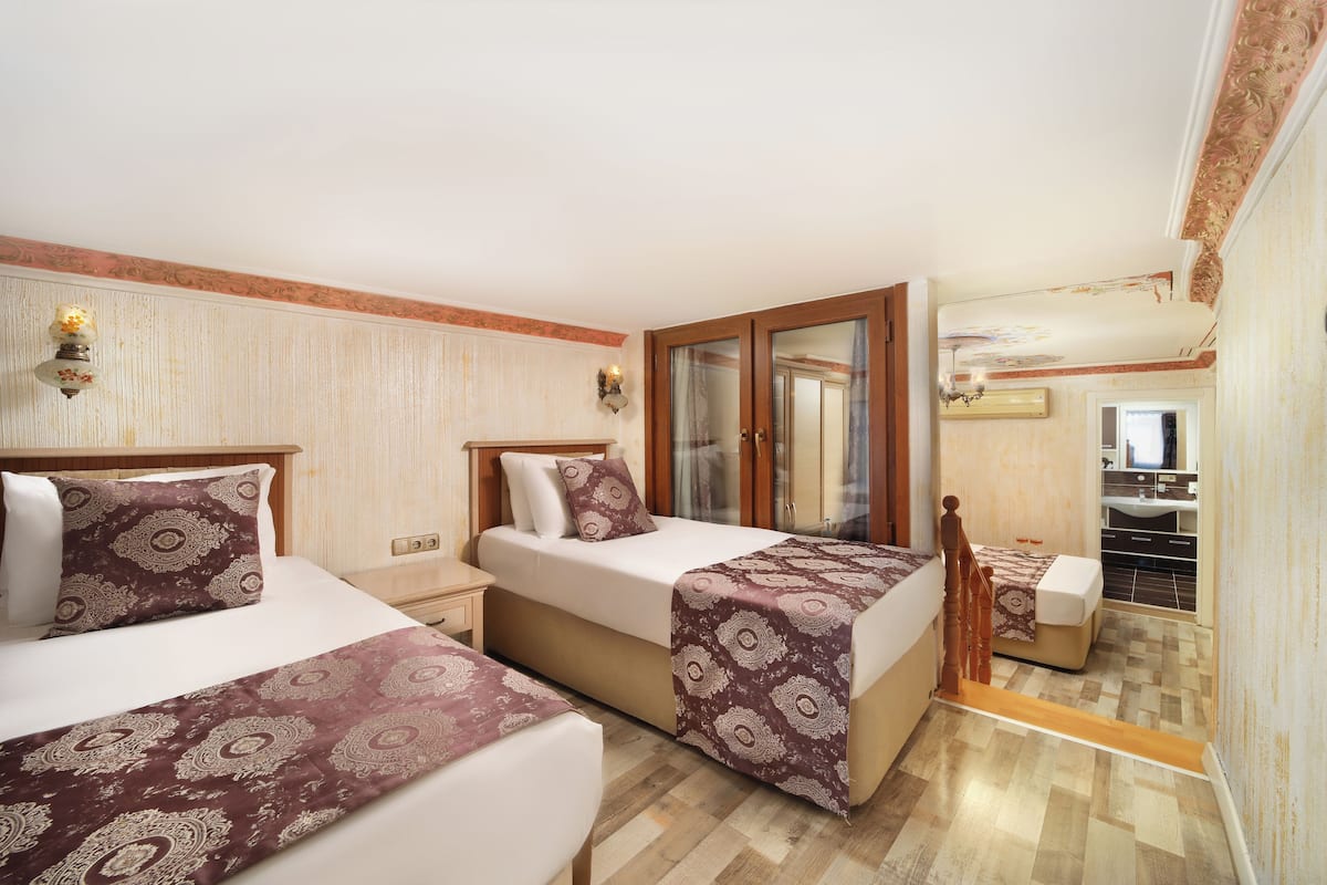 A hotel room with two beds, a bathroom, and a small sitting area.