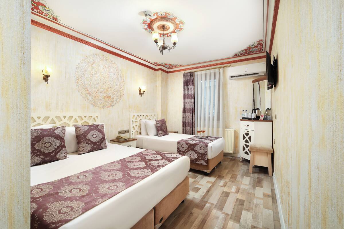 A hotel room with two beds, a desk, and a mirror.