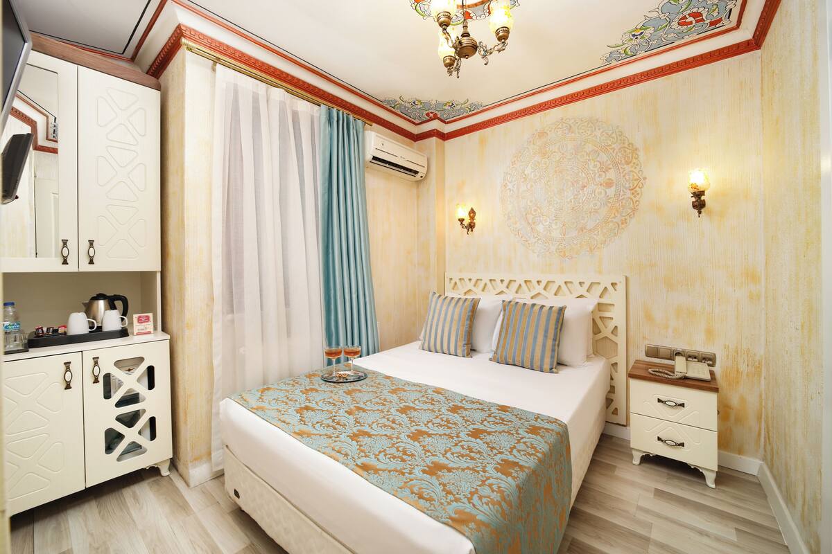 A hotel room with a bed, a nightstand, a wardrobe, and a chandelier.