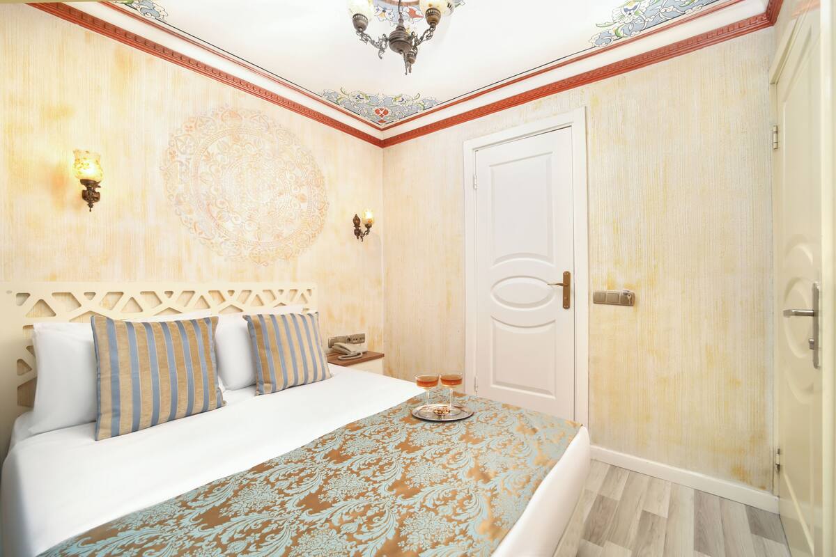 A hotel room with a bed, a nightstand, a decorative wall, and a door.