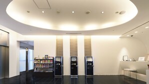 A modern lobby with a circular ceiling light, vending machines, and a reception desk. - Sotetsu Fresa Inn Shimbashi-Karasumoriguchi (Tokyo)