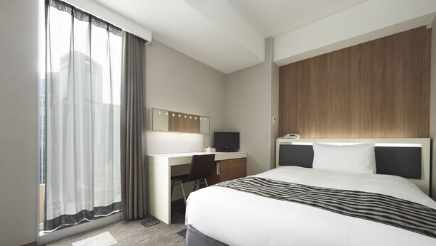 A hotel room with a large bed, a desk with a chair, a television, and a window with sheer curtains. - Sotetsu Fresa Inn Shimbashi-Karasumoriguchi (Tokyo)