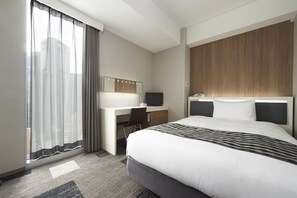 A hotel room with a large bed, a desk with a chair, a television, and a window with sheer curtains. - Sotetsu Fresa Inn Shimbashi-Karasumoriguchi (Tokyo)