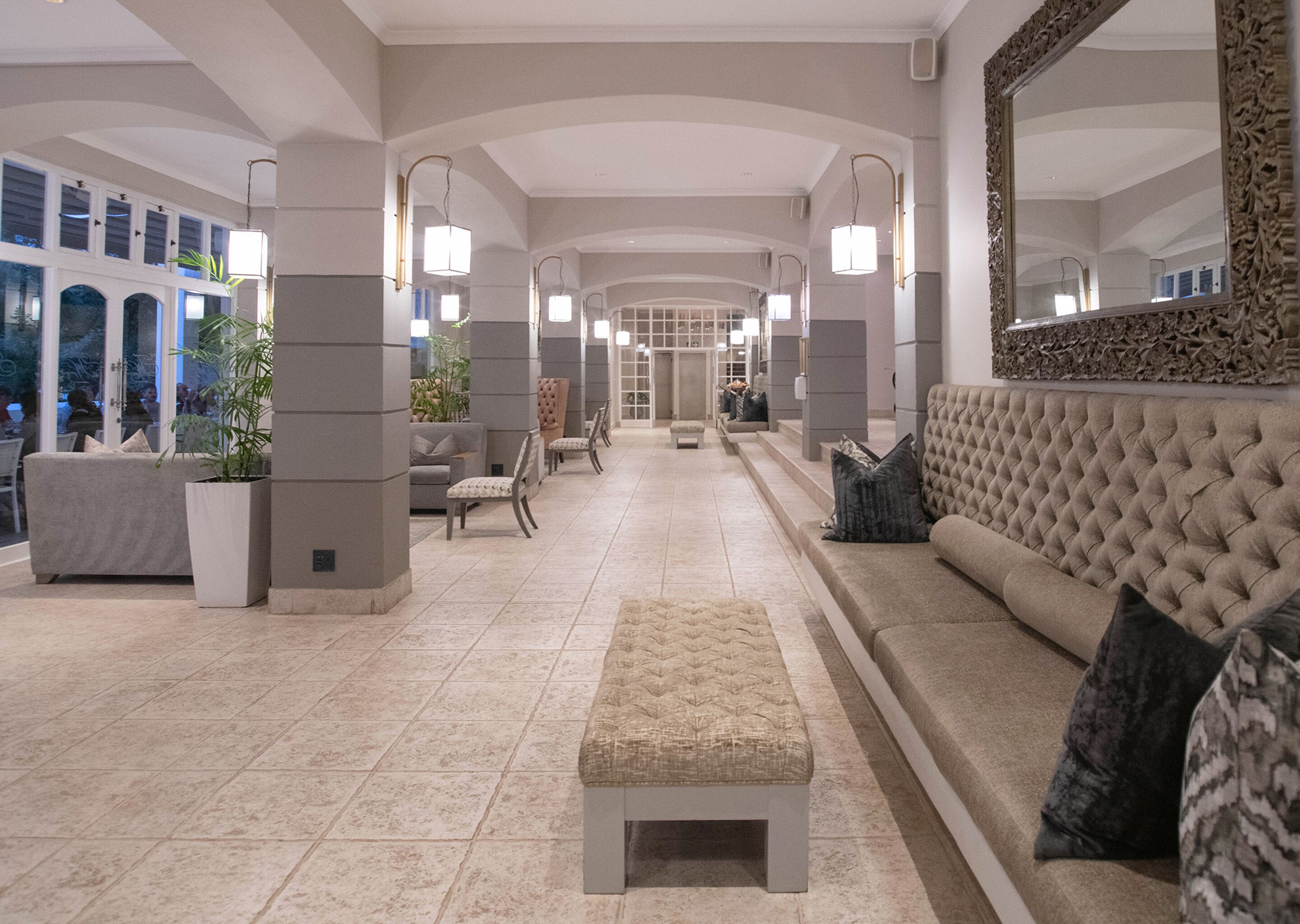 A spacious lobby with a central seating area, a large mirror, and a view of the outdoors.