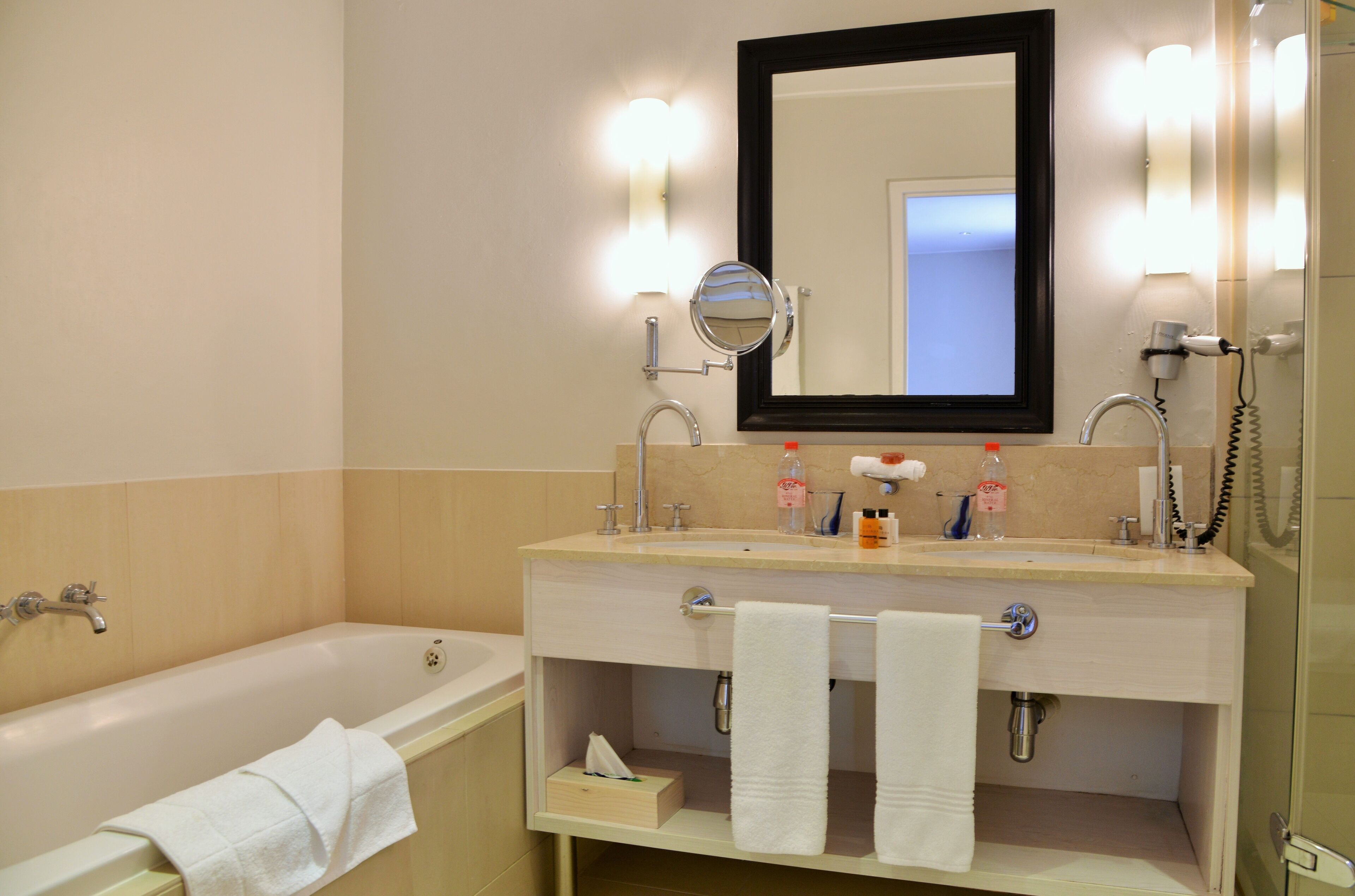 A bathroom with a bathtub, a sink with a mirror, and a hairdryer.