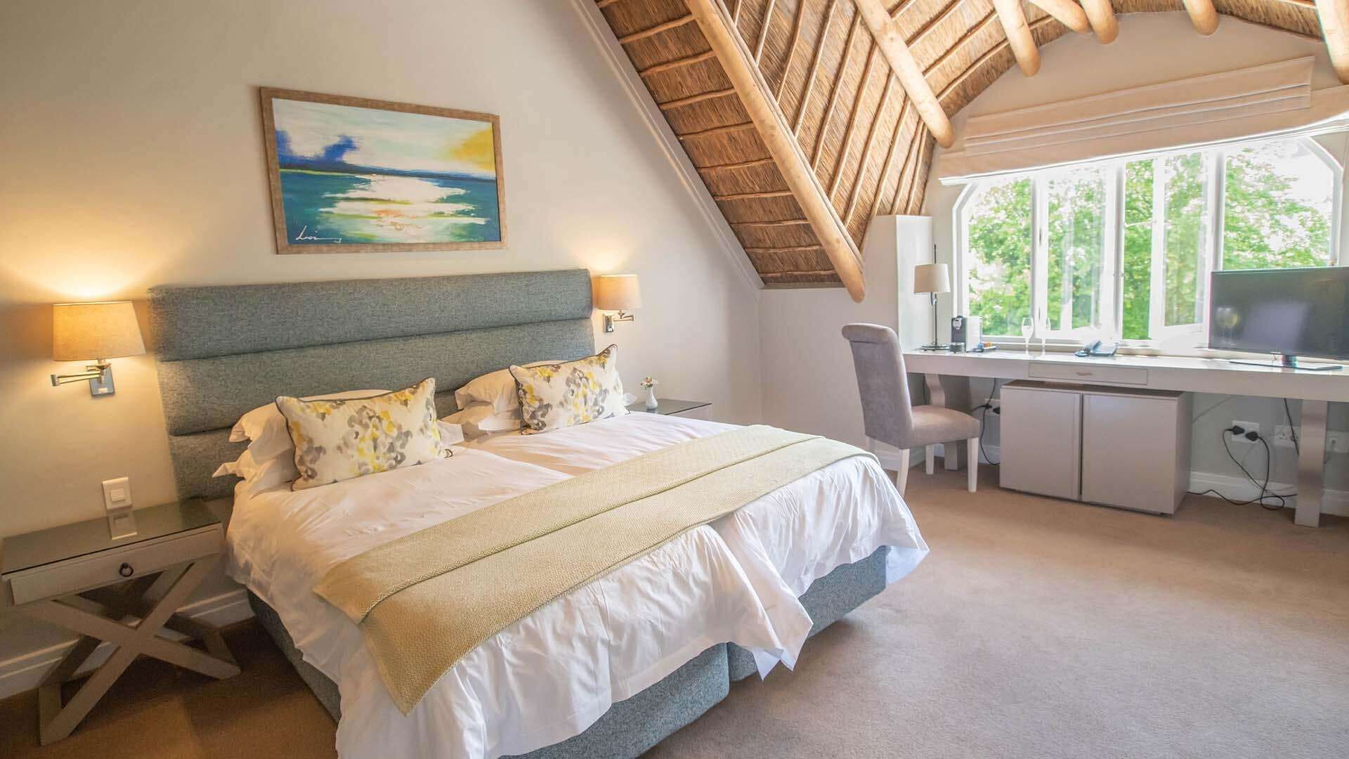 Une chambre à coucher avec un lit, des lampes de chevet, un bureau et un ordinateur.