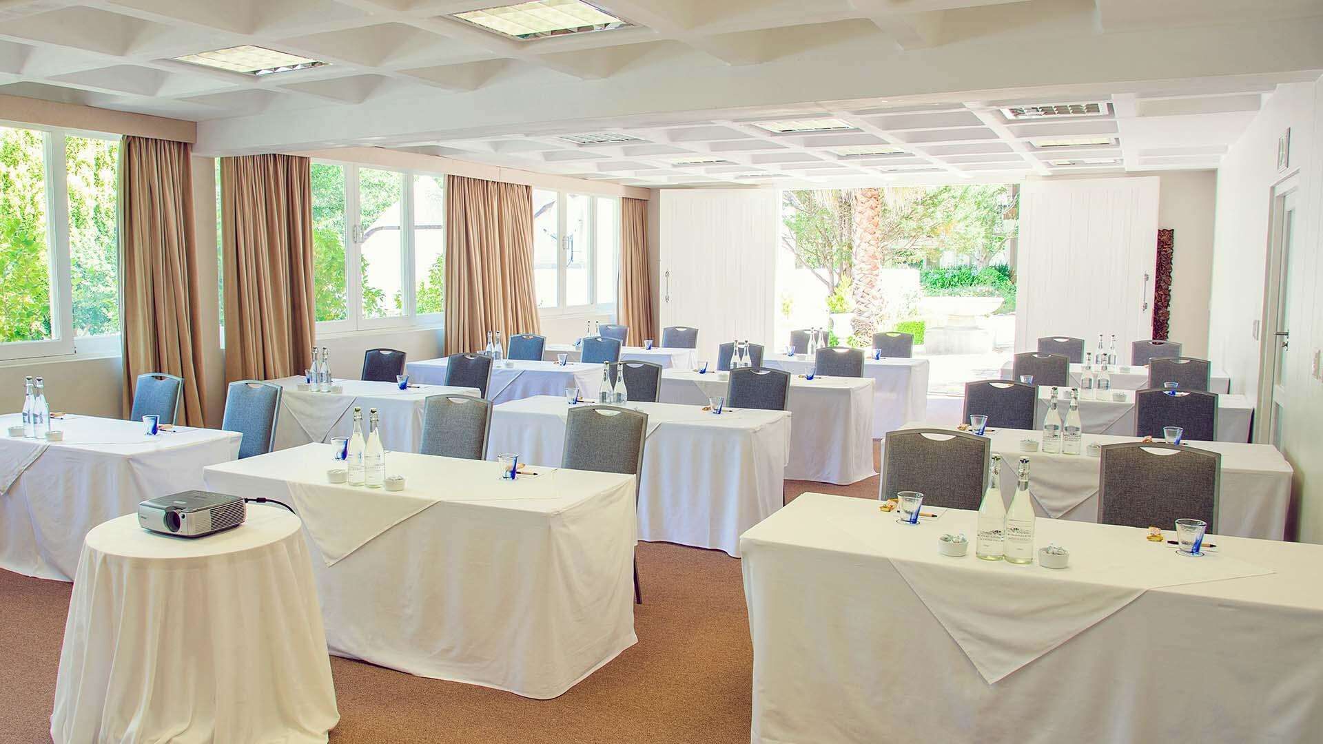 Un salón de conferencias con varias mesas, sillas y un proyector.