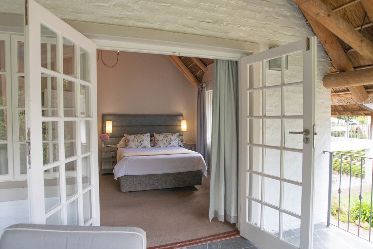 A bedroom with a bed, bedside lamps, and a view of the outdoors.