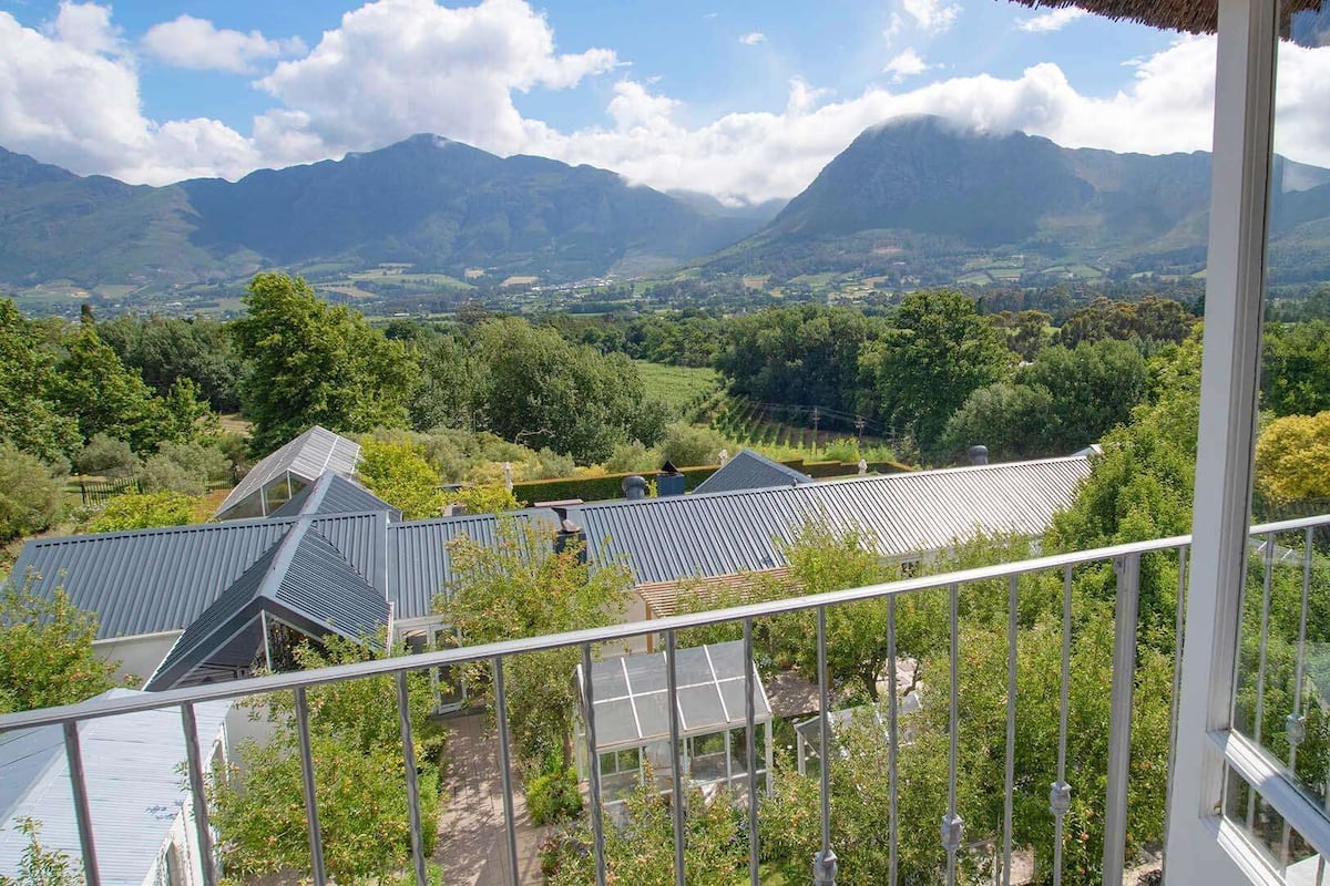 A balcony with a view of a valley, mountains, and solar panels on buildings.