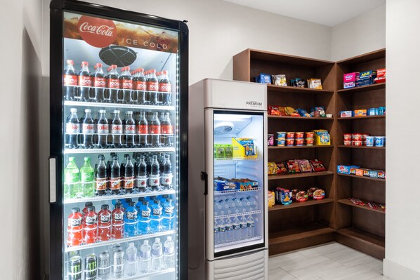 A vending machine stocked with various beverages and a refrigerator stocked with food items.