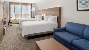 Une chambre d’hôtel avec deux lits, un canapé, un bureau et une chaise.