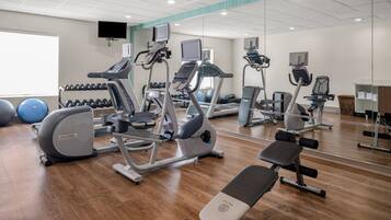 A gym with cardio machines, dumbbells, and exercise balls.