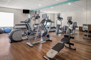 A gym with cardio machines, dumbbells, and exercise balls.