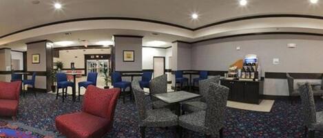 A hotel lobby with a curved ceiling, seating areas with patterned chairs, and a reception desk.