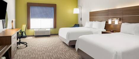 A hotel room with two beds, a desk, a chair, a TV, and a window with a view.