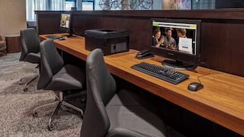 Un cubículo de oficina moderno con una computadora de escritorio, teclado, ratón y un monitor grande mostrando una página web.