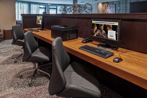 Un cubículo de oficina moderno con una computadora de escritorio, teclado, ratón y un monitor grande mostrando una página web.