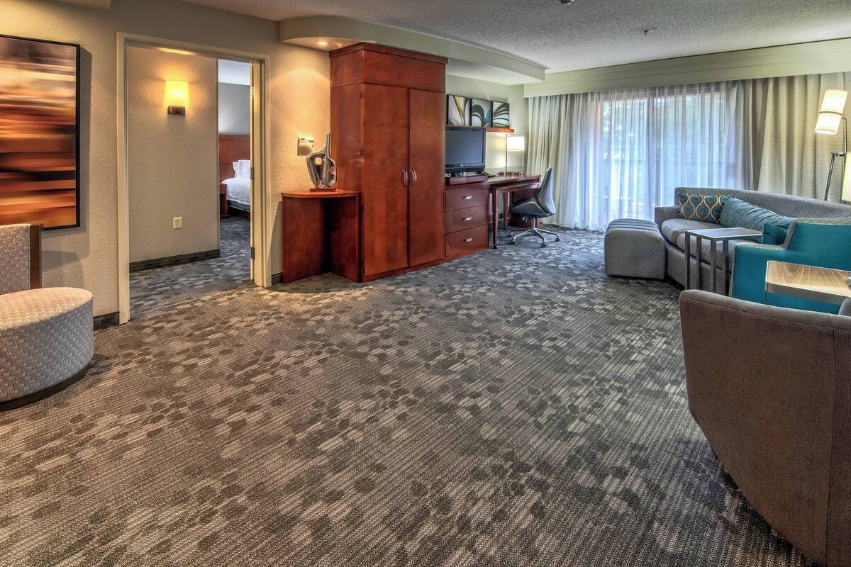 A hotel room with a large wardrobe, a desk, a sofa, and a television.