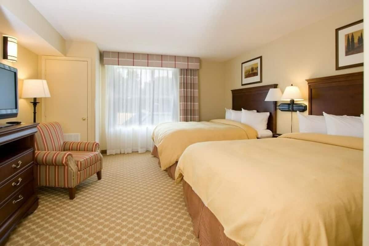 Une chambre d’hôtel avec deux lits, une télévision, une chaise et un bureau.