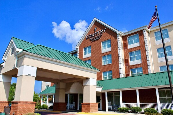 A Country Inn & Suites by Radisson building with a green roof, brick facade, and a covered entrance area.
