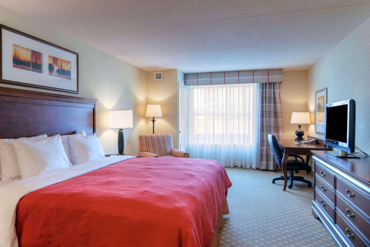 Une chambre d’hôtel avec un grand lit, un bureau équipé d’un ordinateur, une chaise et un téléviseur.