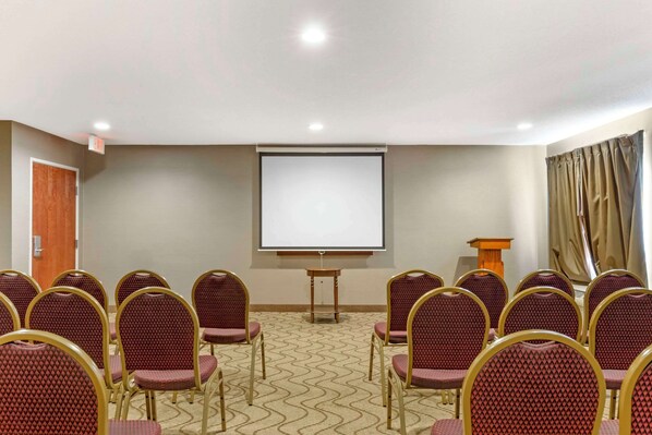 A conference room with rows of chairs, a projector screen, and a podium.