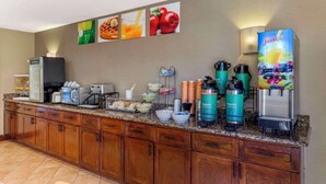 A hotel kitchen with a coffee station, a juice dispenser, and a microwave. - Quality Inn Raleigh Downtown (Raleigh)