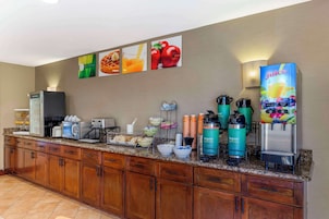 Una cocina de hotel con una estación de café, un dispensador de jugo y un microondas.