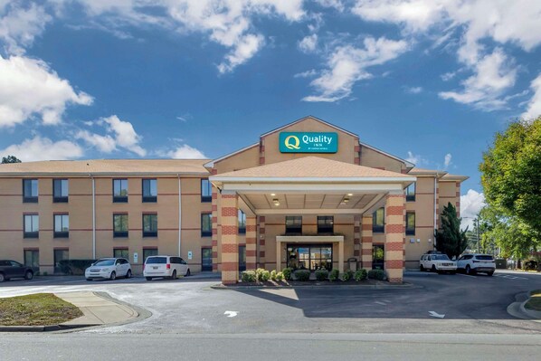Een Quality Inn hotel met een overdekte ingang, meerdere parkeerplaatsen en een helderblauwe lucht.