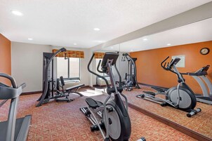 Un gimnasio con diversos equipos de ejercicio, incluyendo cintas de correr y elípticas.
