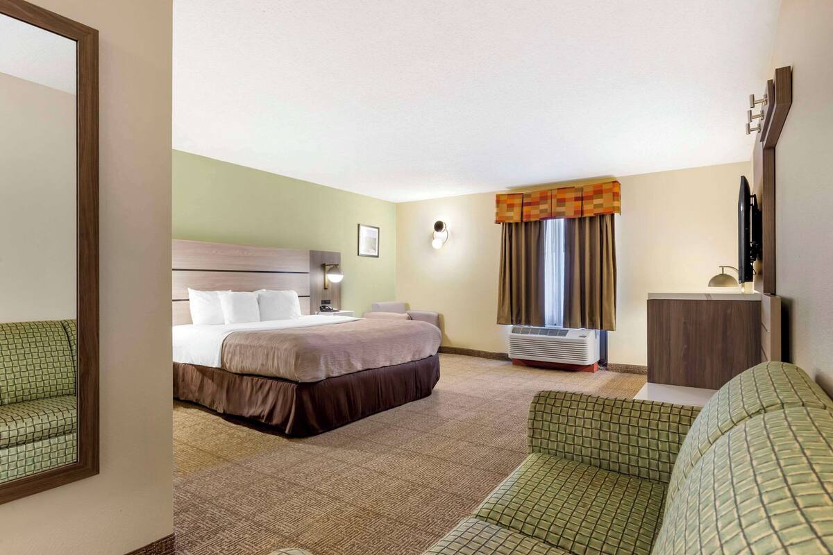 A hotel room with a bed, a desk, a chair, and a television.