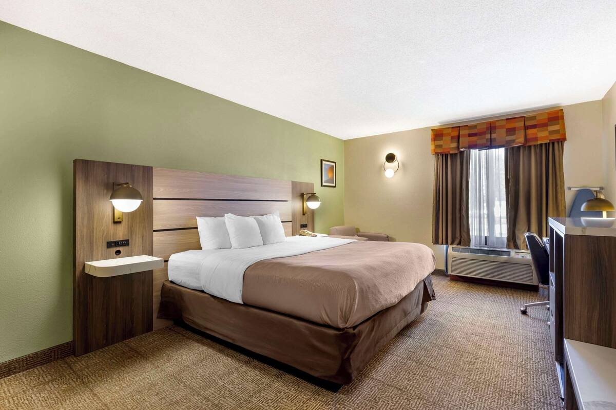 A hotel room with a large bed, bedside tables, a desk, and a chair.
