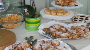 A buffet table with various pastries and a potted orchid. - Hotel Marina (Massa)
