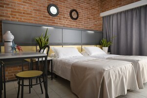 Habitación de hotel con dos camas, una mesa de comedor, sillas y plantas en macetas.