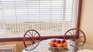 Une table à manger avec des chaises, un panier de fruits et des assiettes.