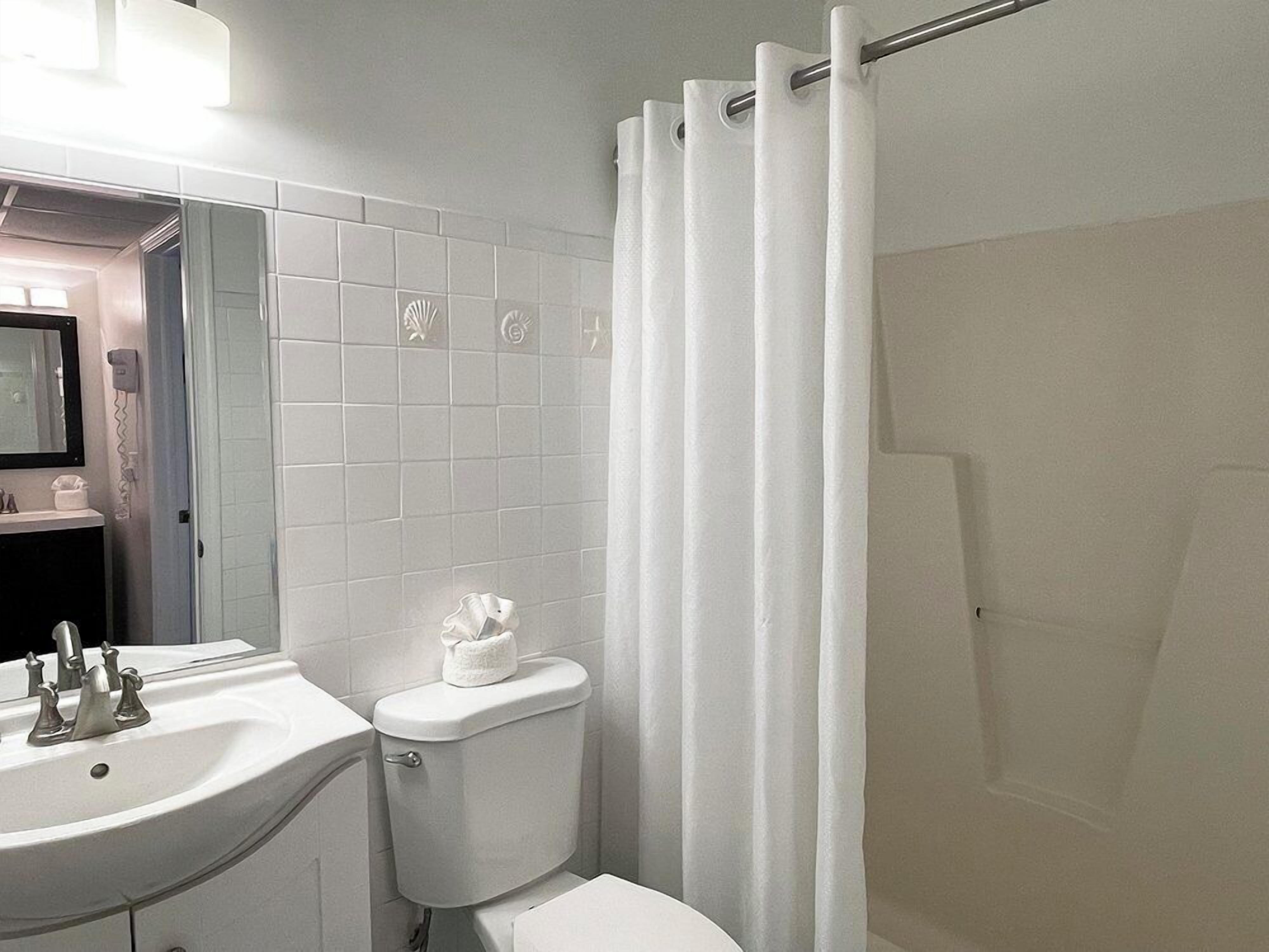 A bathroom with a white sink, toilet, and shower curtain.