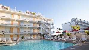 Un hôtel doté d’une piscine, de plusieurs balcons et de chaises longues.