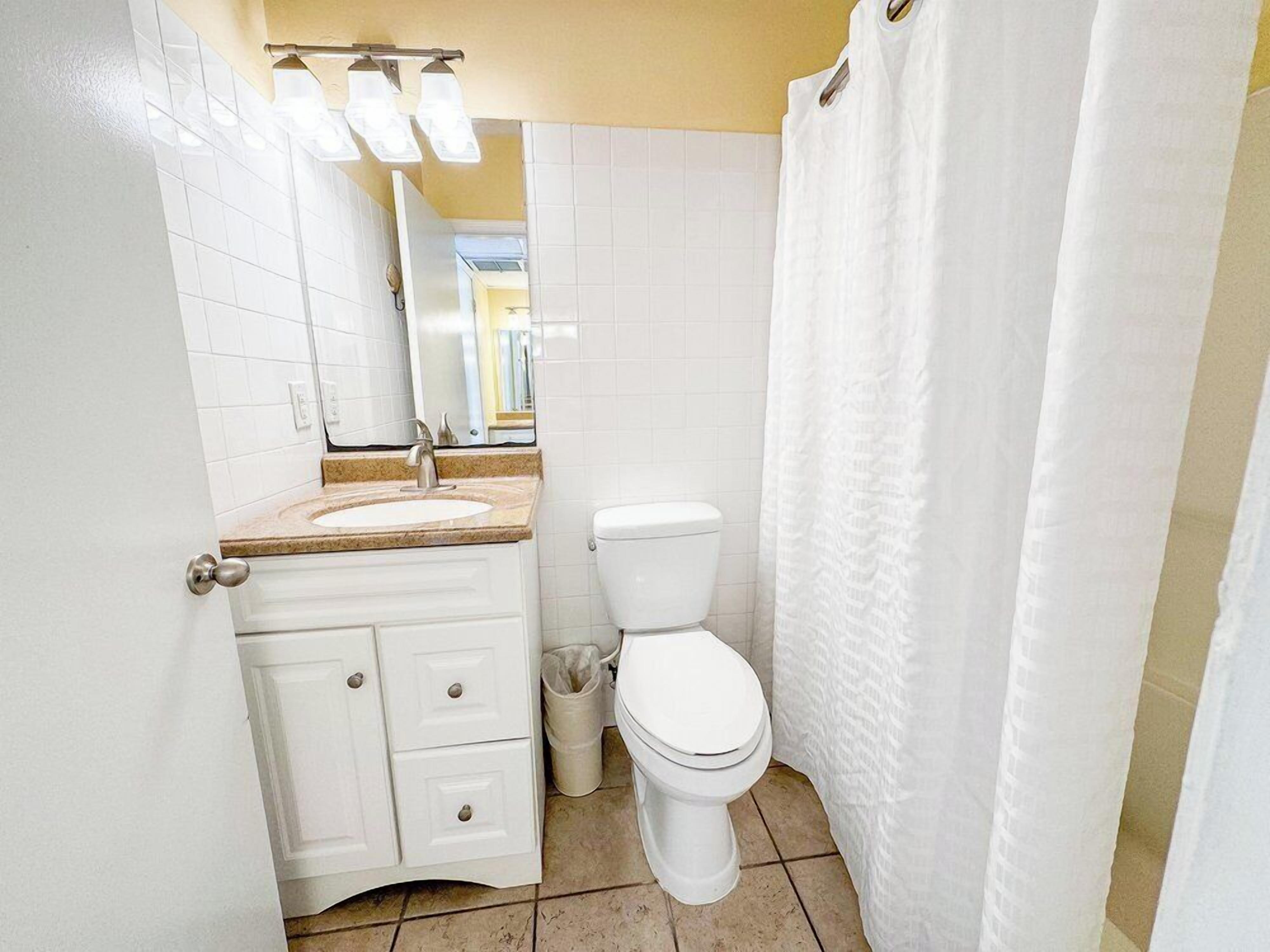 Une salle de bain avec un lavabo blanc, des toilettes et un rideau de douche.