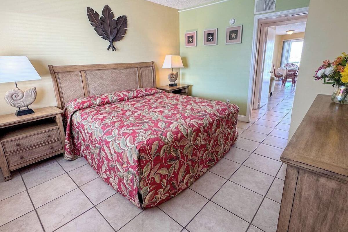 Een slaapkamer met een bed, nachtkastjes, een bladdecoratie aan de muur en sterdecoraties in lijstjes.