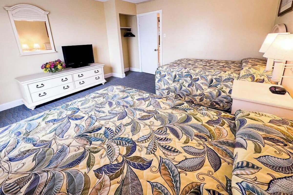 Een hotelkamer met een bed, een dressoir, een televisie en een deur naar een kast.