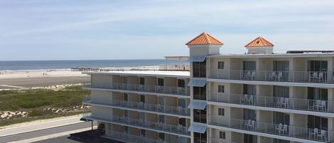 A multi-story hotel with balconies, a beach view, and a parking lot.