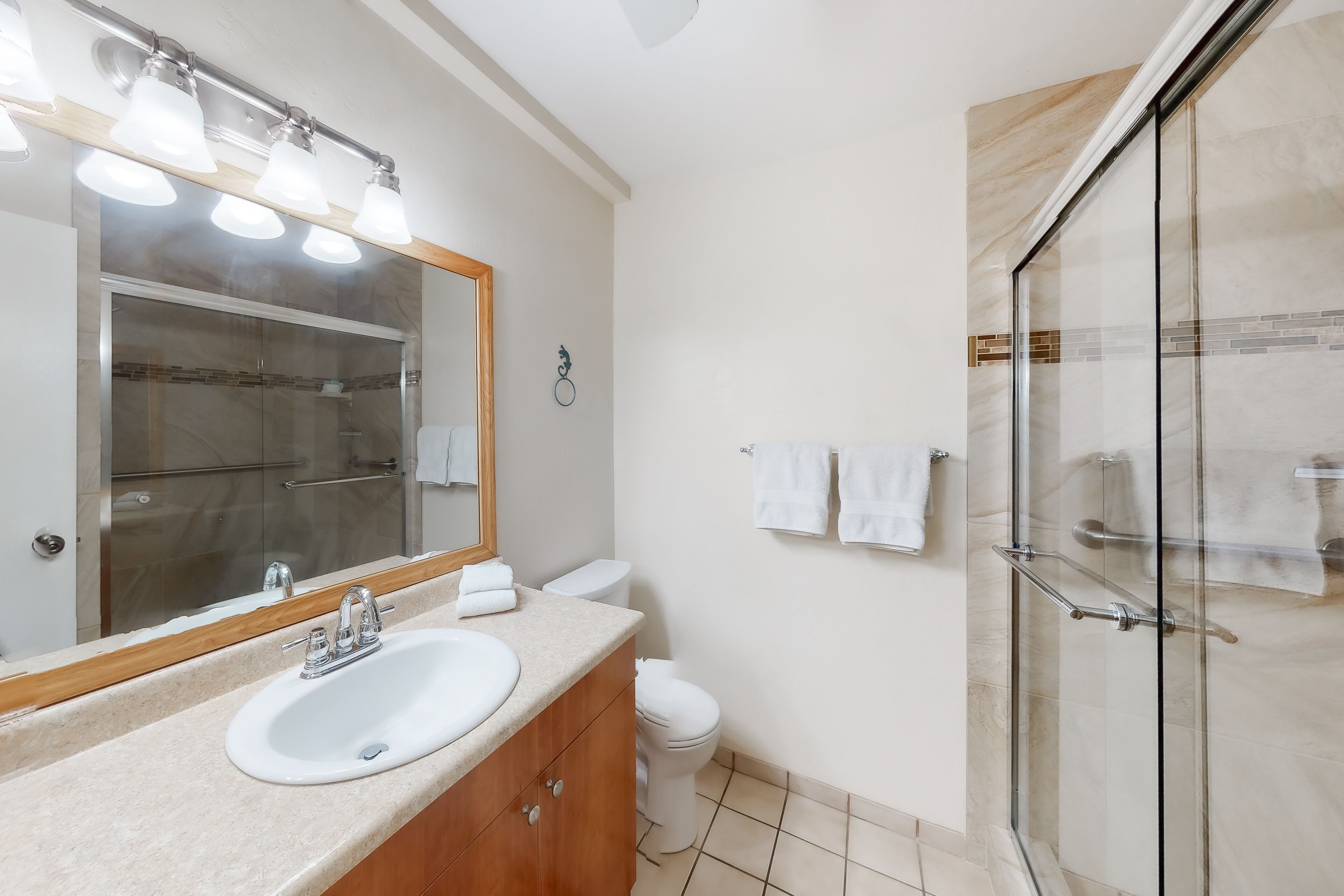 Een moderne badkamer met een grote spiegel, een wastafel, een toilet en een douchecabine met glazen wanden.