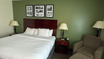 Una habitación de hotel con cama, dos mesitas de noche, una silla y una pared decorada con cuadros.