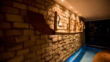 A swimming pool with a brick wall and stone sculptures.