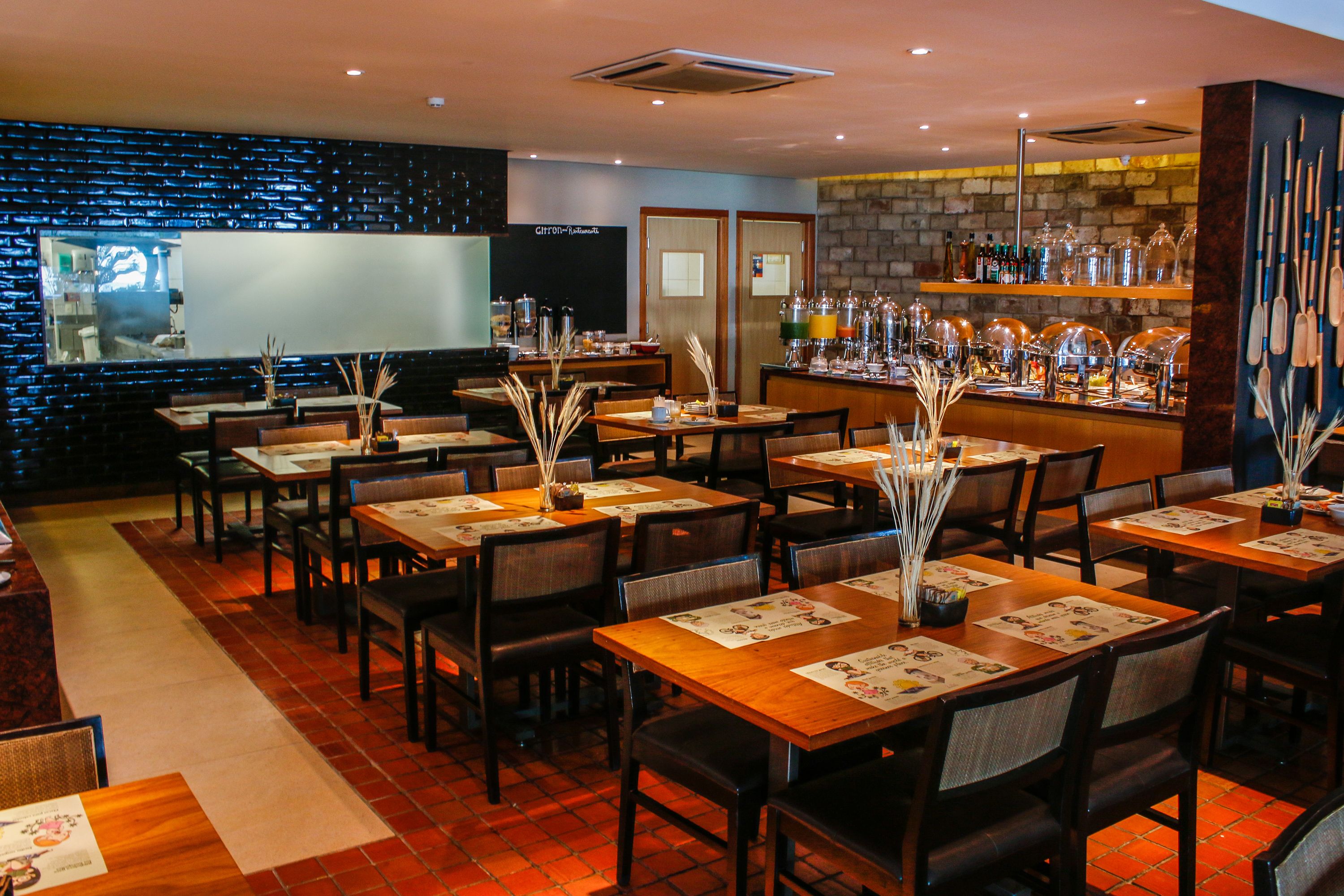 A restaurant with multiple tables, chairs, and a bar area with shelves of bottles.